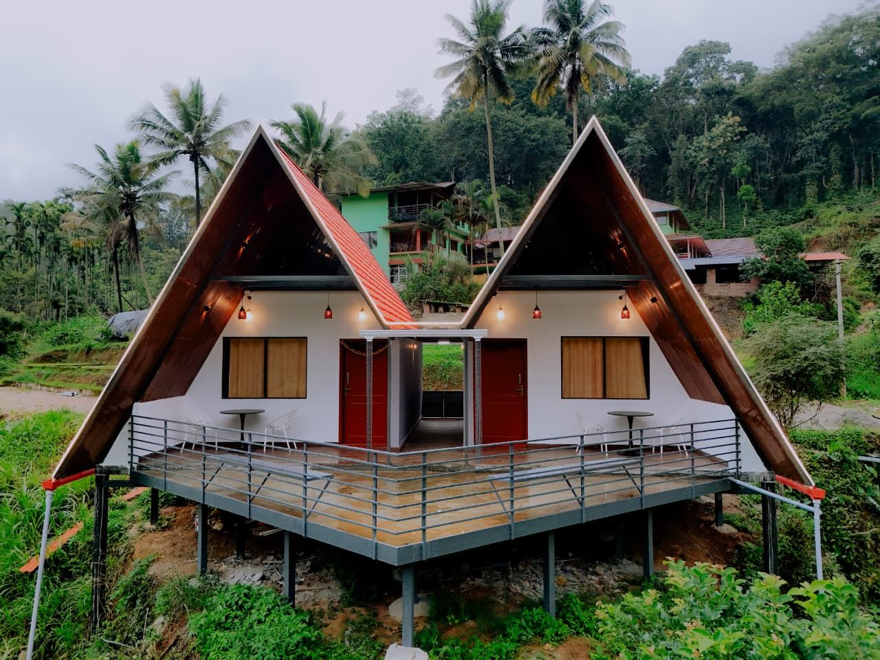The two A-frame cottages of Coorg Natures Retreat on their raised deck